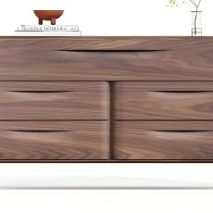 Home A modern chest of drawers crafted from dark brown wood with a pronounced natural wood grain. The minimalist design features six drawers arranged in two columns: three narrower ones on the left and three wider ones on the right, each with sleek, recessed handles. The piece is elevated on four slender, slightly splayed metal legs. The top is styled with a hardcover book and a small decorative object, placed against a clean, neutral background to highlight its elegant form and functional design.